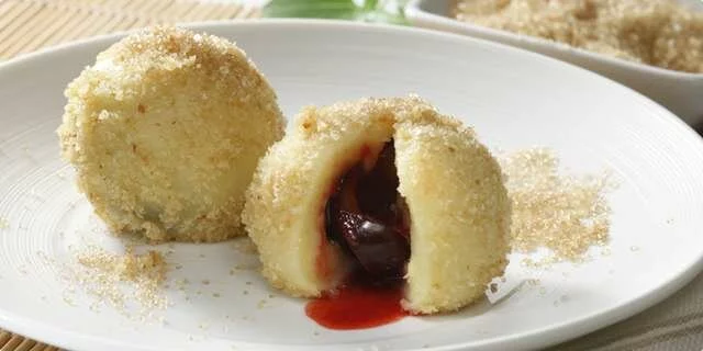 Bolinhas de massa com ameixas e pães ralados e canela cozidos